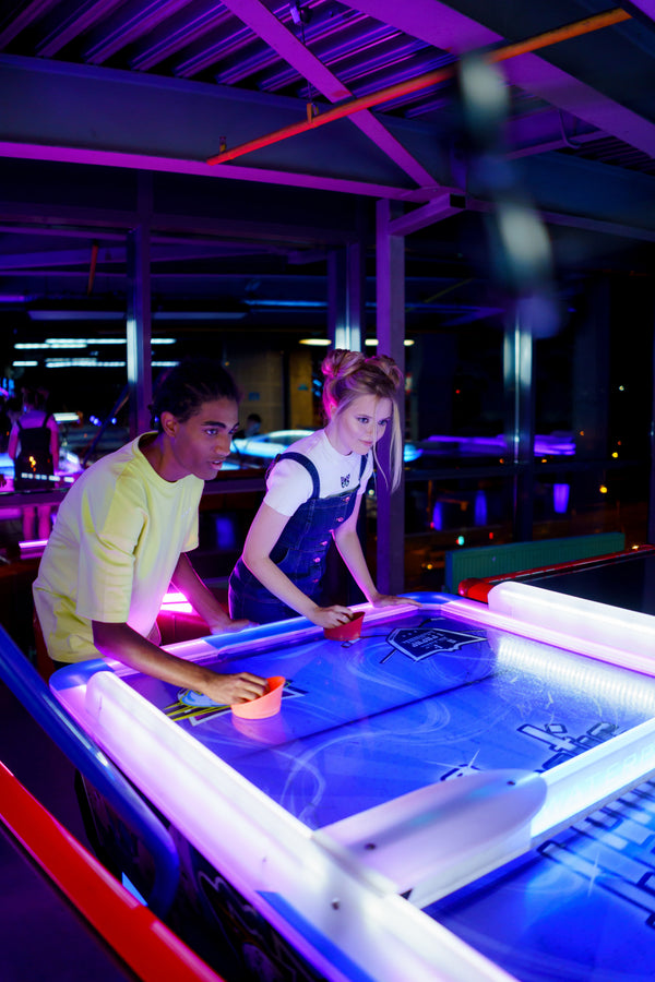 People playing arcade games in neon-lit venue